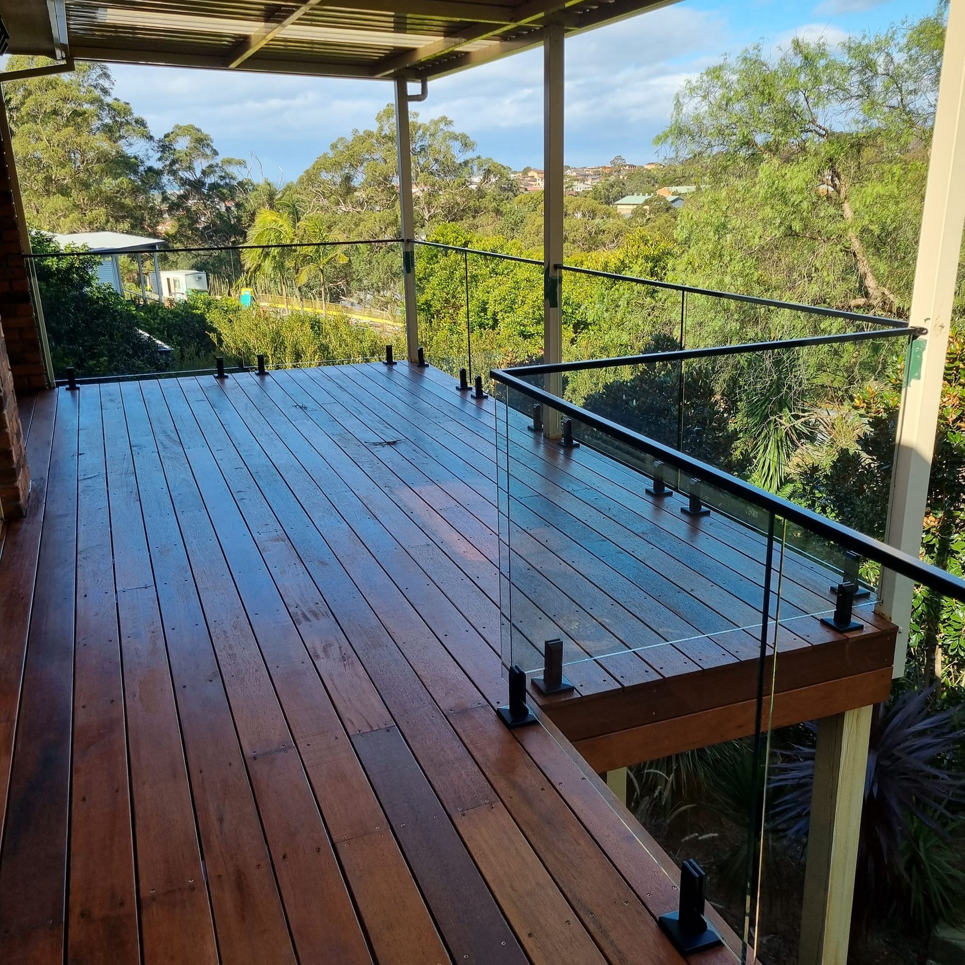 Spacious Wooden Deck With Glass Railings Overlooking Trees