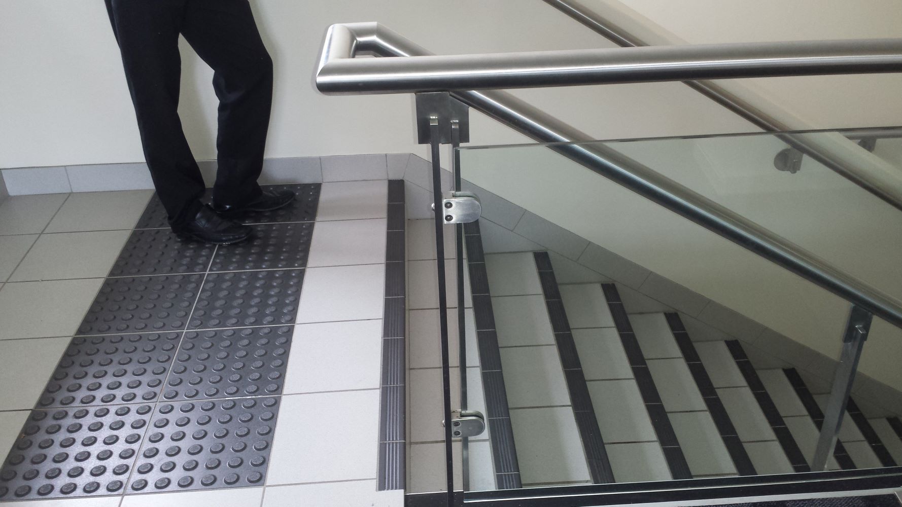 A Person Standing on a Tiled Floor Next to a Staircase — D & T Balustrade Systems In Unanderra, NSW