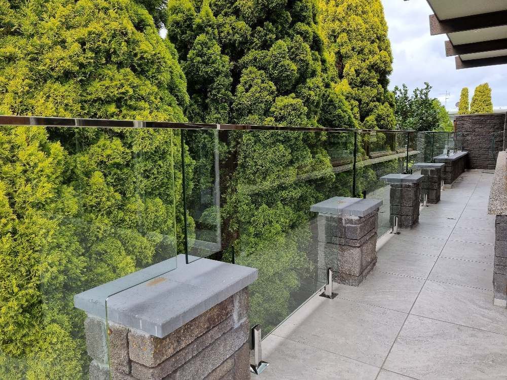 A Balcony With a Glass Railing and Trees in the Background — D & T Balustrade Systems In Unanderra