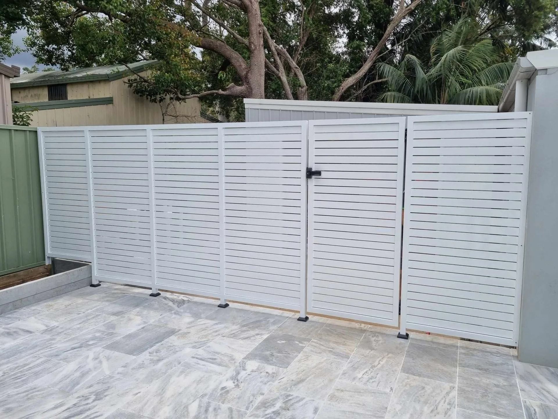 A White Gate is Sitting on Top of a Concrete Driveway — D & T Balustrade Systems In Unanderra, NSW