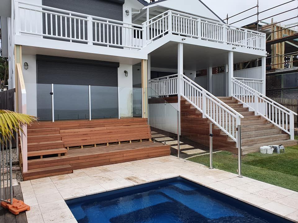 White house with wood deck, steps, pool, and railing — D & T Balustrade Systems In Unanderra, NSW