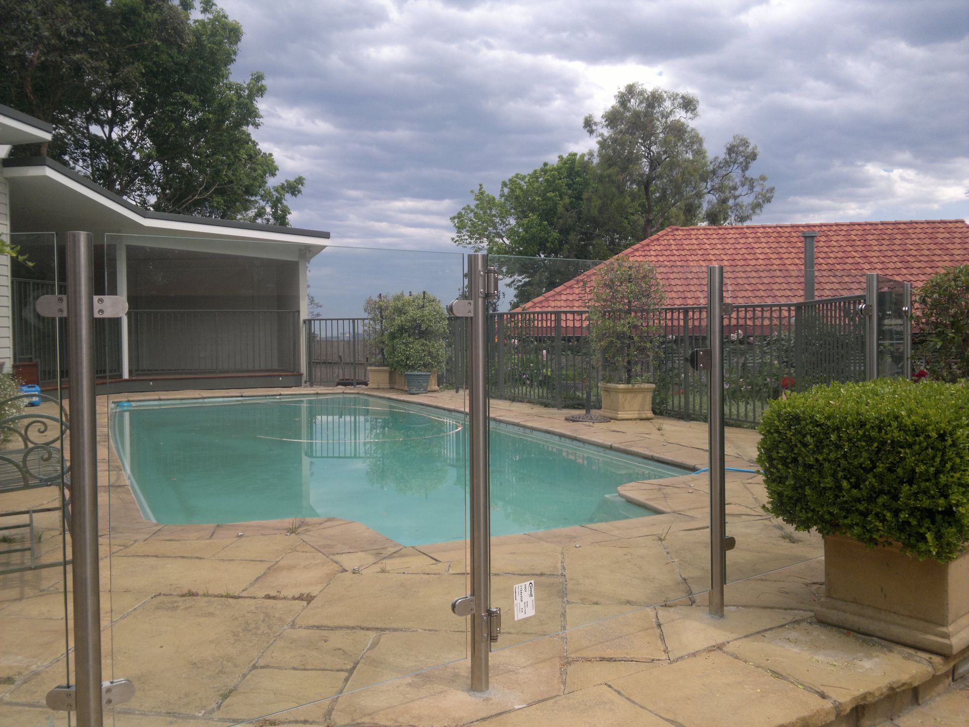 There is a Large Swimming Pool in the Backyard of a House — D & T Balustrade Systems In Shellharbour, NSW