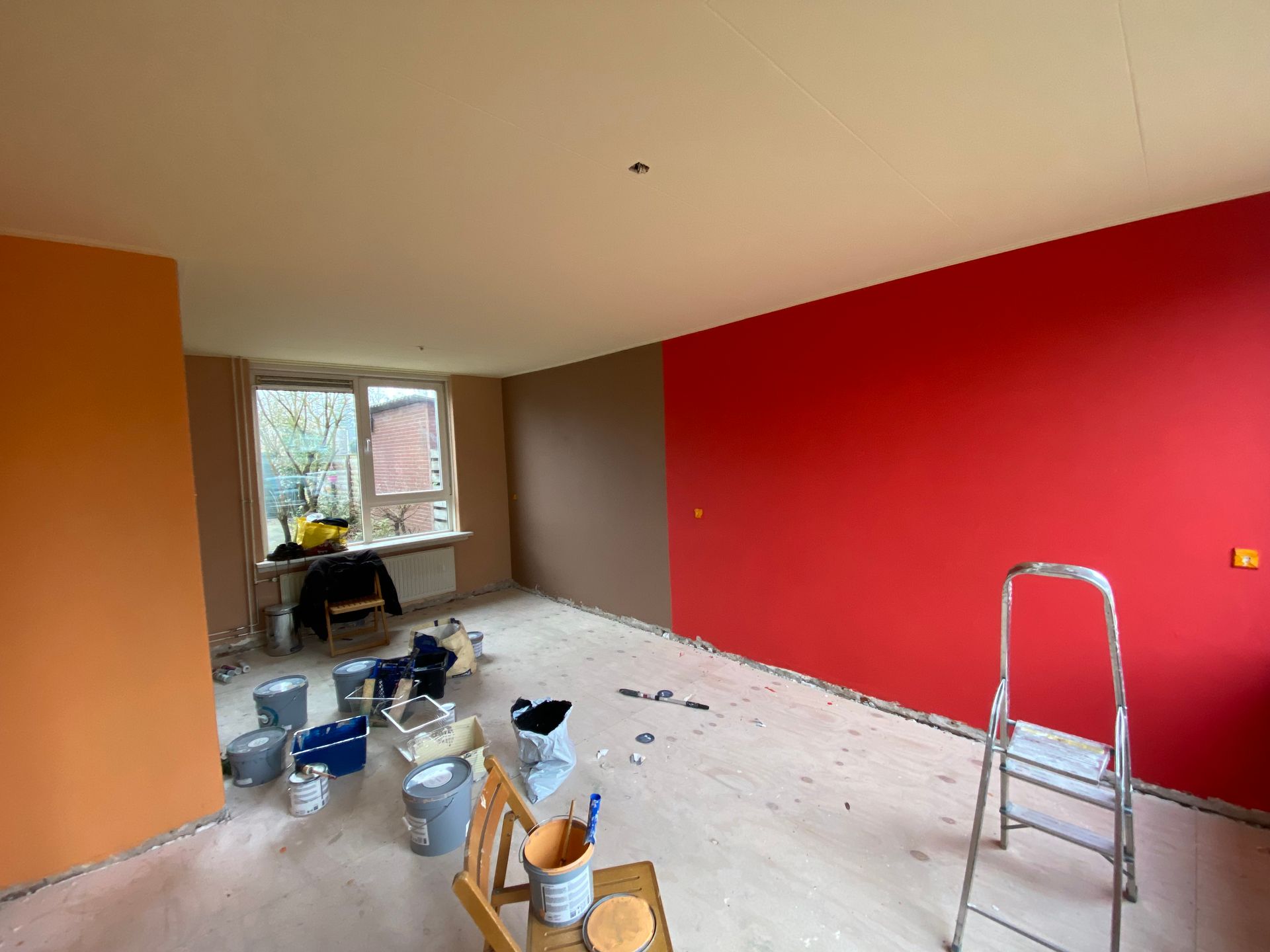 Kamer met vers geverfde muren: oranje, rood en bruin, en geel op het plafond.
7 kleuren in het hele huis.