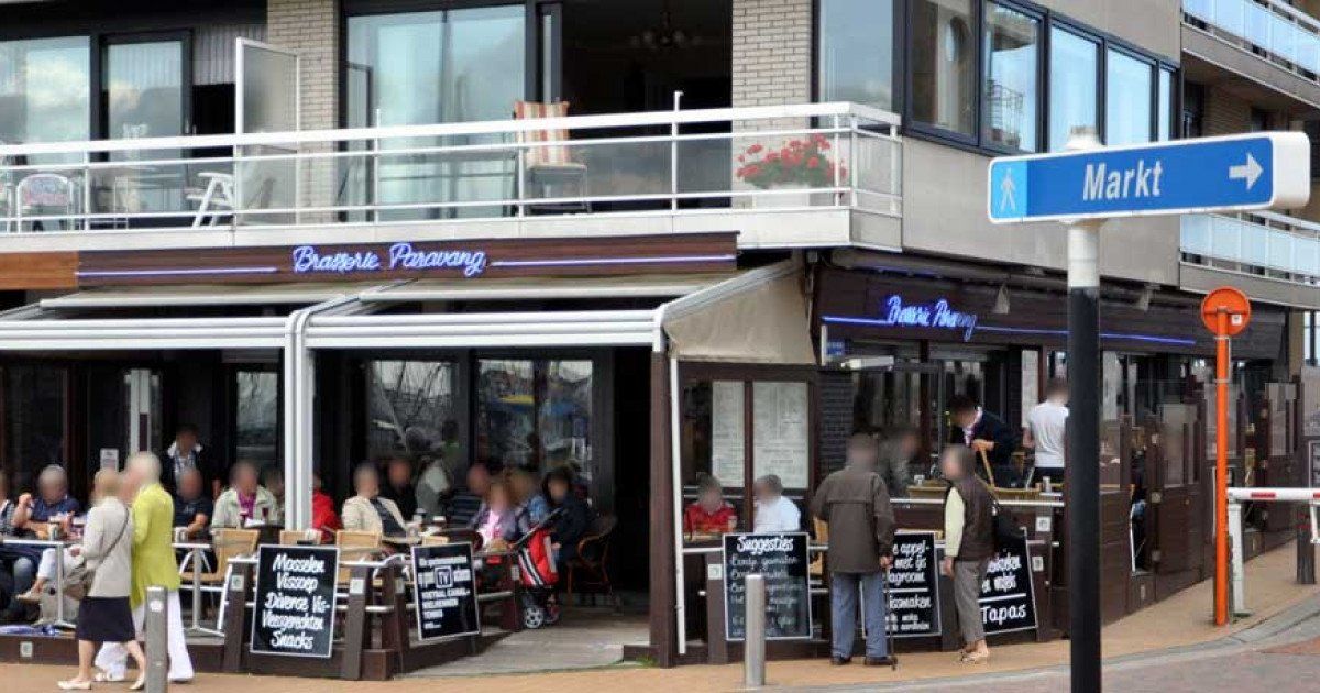 Een groep mensen staat buiten een restaurant.