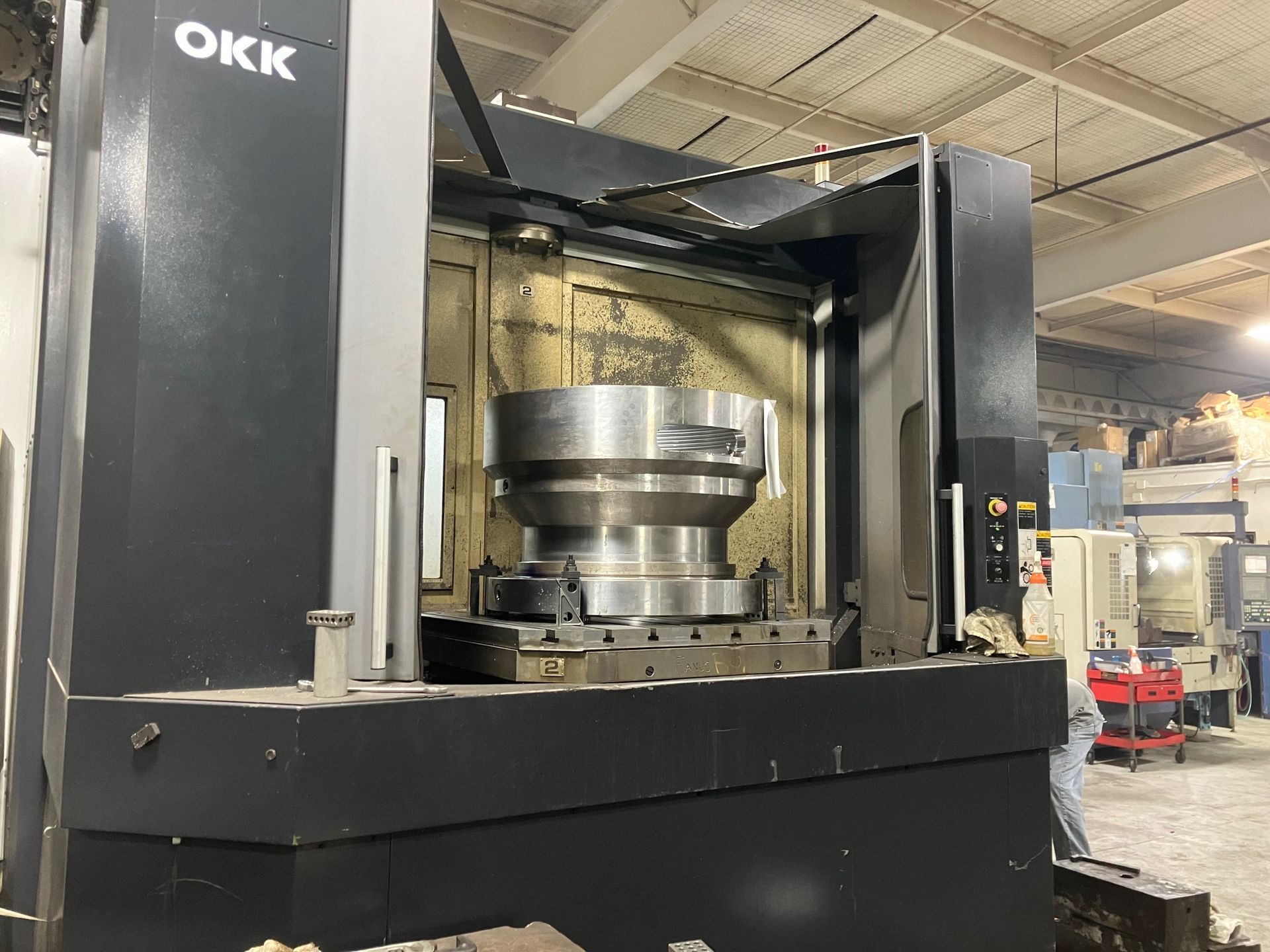 A large machine with the word okk on it is in a factory.