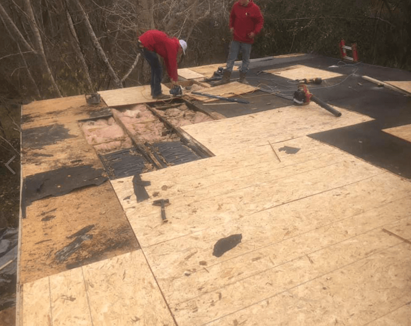 Men laying down plywood for new roof