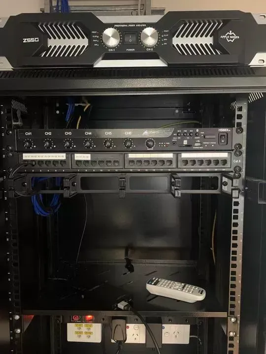 A black equipment rack with audio components, including an amplifier and mixer