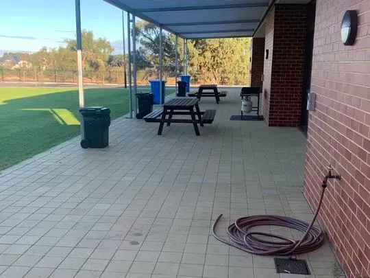 A covered outdoor area with picnic tables and a bbq.