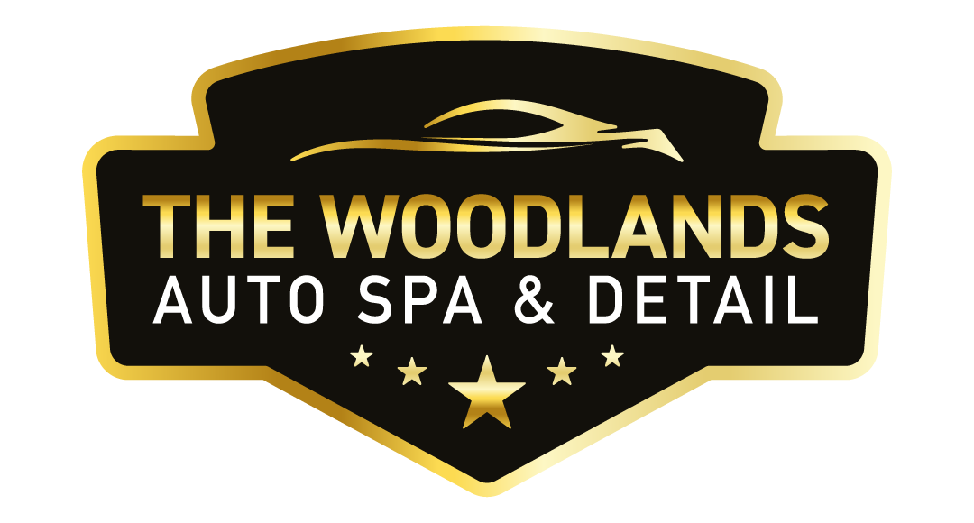 Logo for The Woodlands Auto Spa & Detail, black and gold shield, car silhouette, text, stars.
