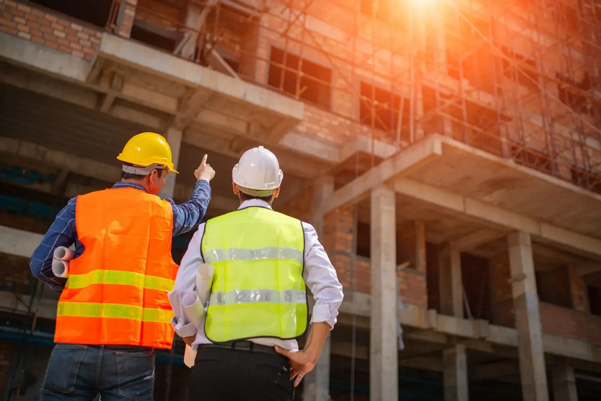 two construction workers pointing at a building with scaffolding