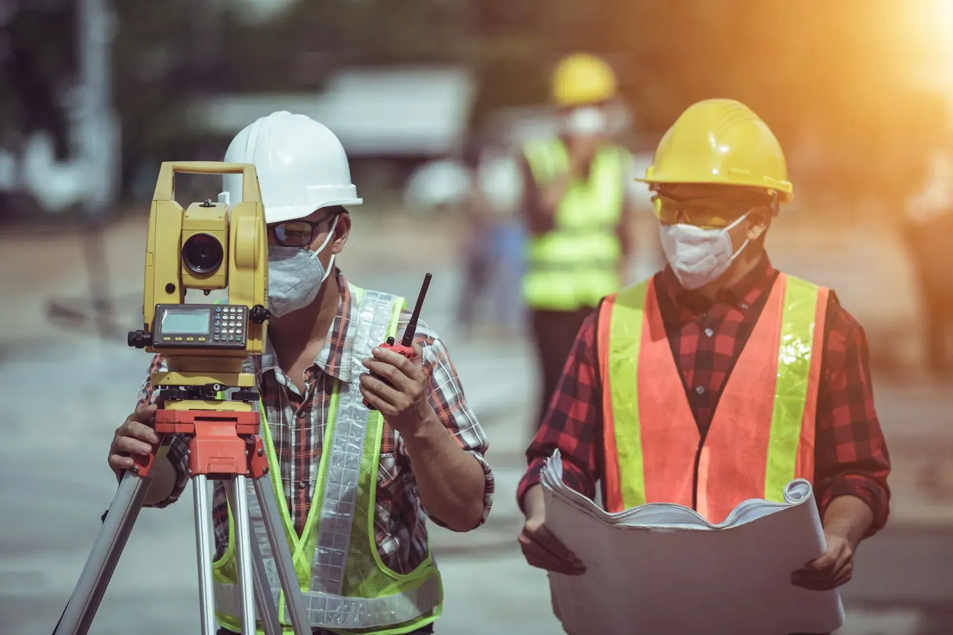 two construction workers using measuring device on the field