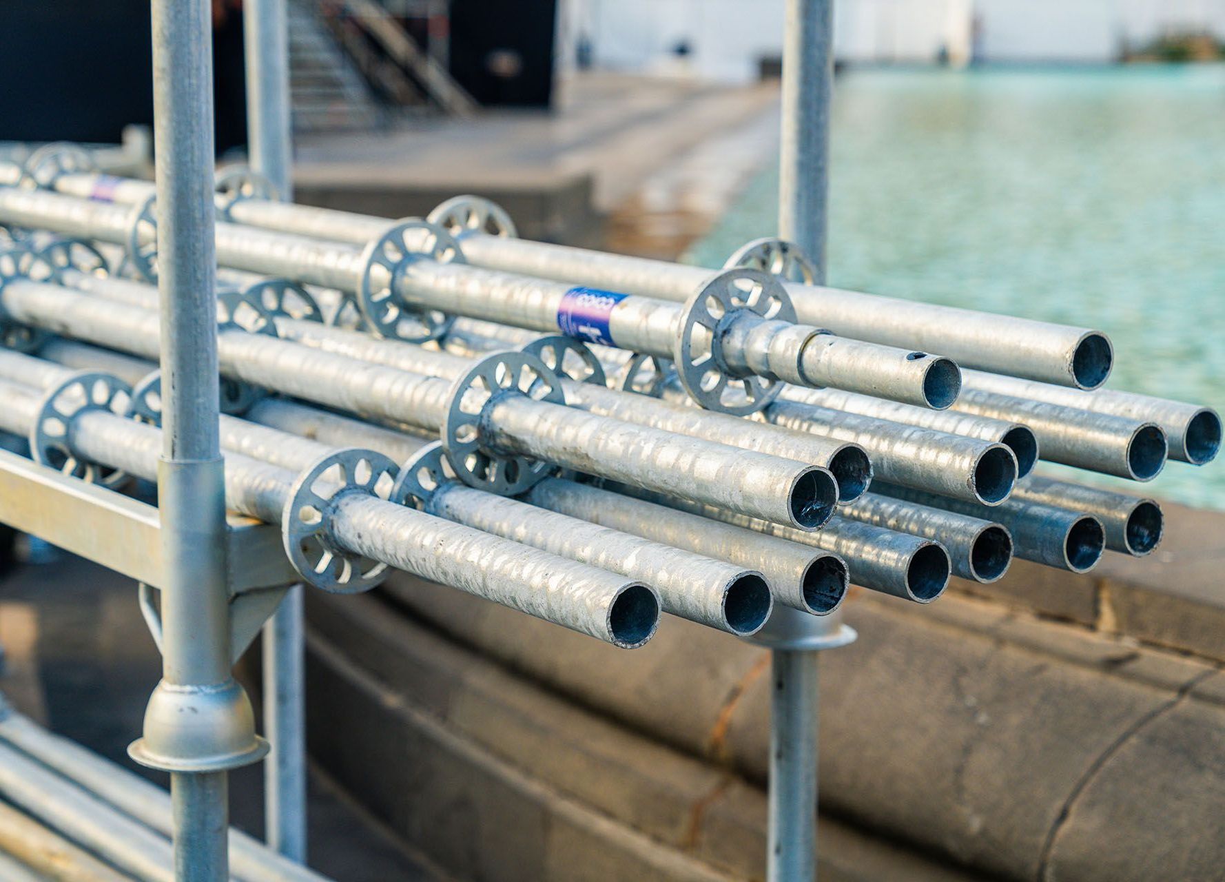 A bunch of metal pipes are stacked on top of each other on a scaffolding.