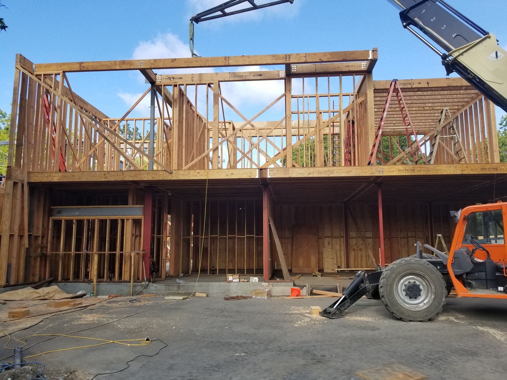 A large wooden house is being built with a crane in front of it.