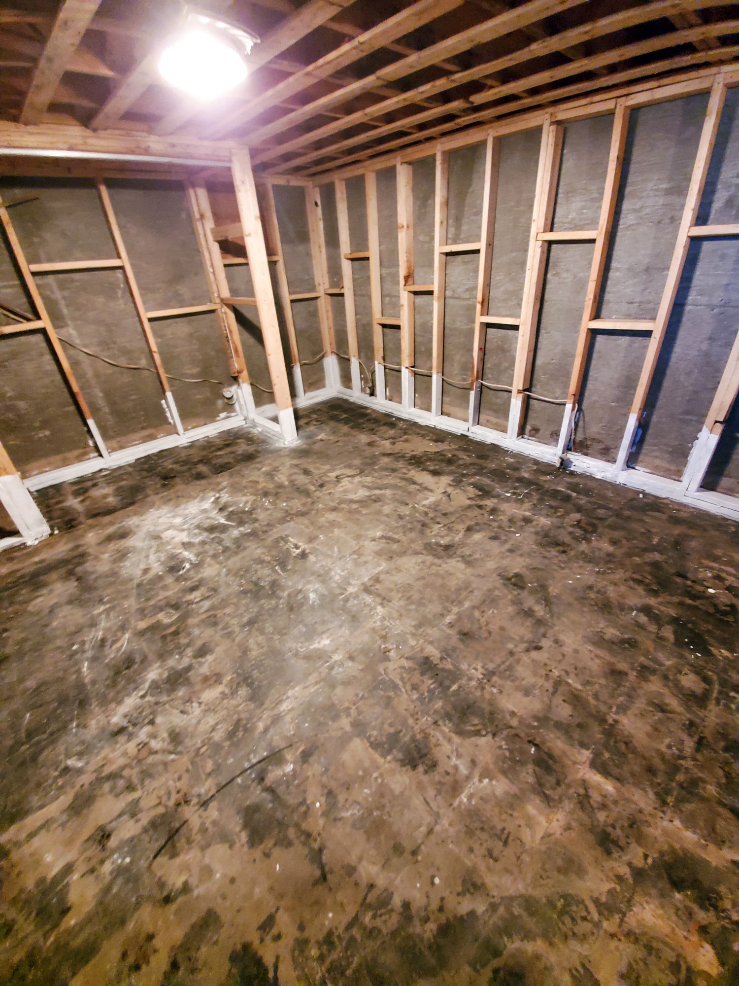 An empty basement with wooden walls and a concrete floor.