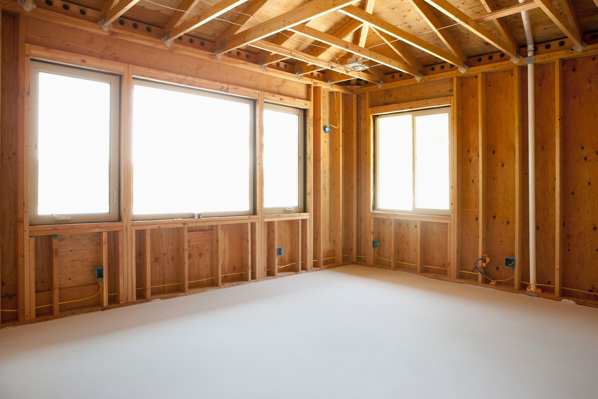 An empty room in a house under construction with wooden walls and windows.