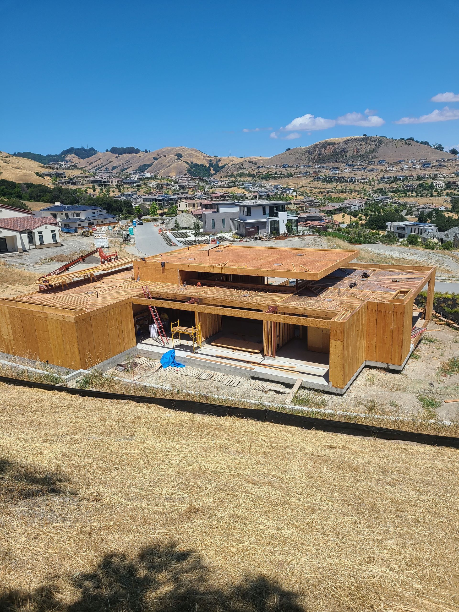 A large wooden house is being built on top of a hill.
