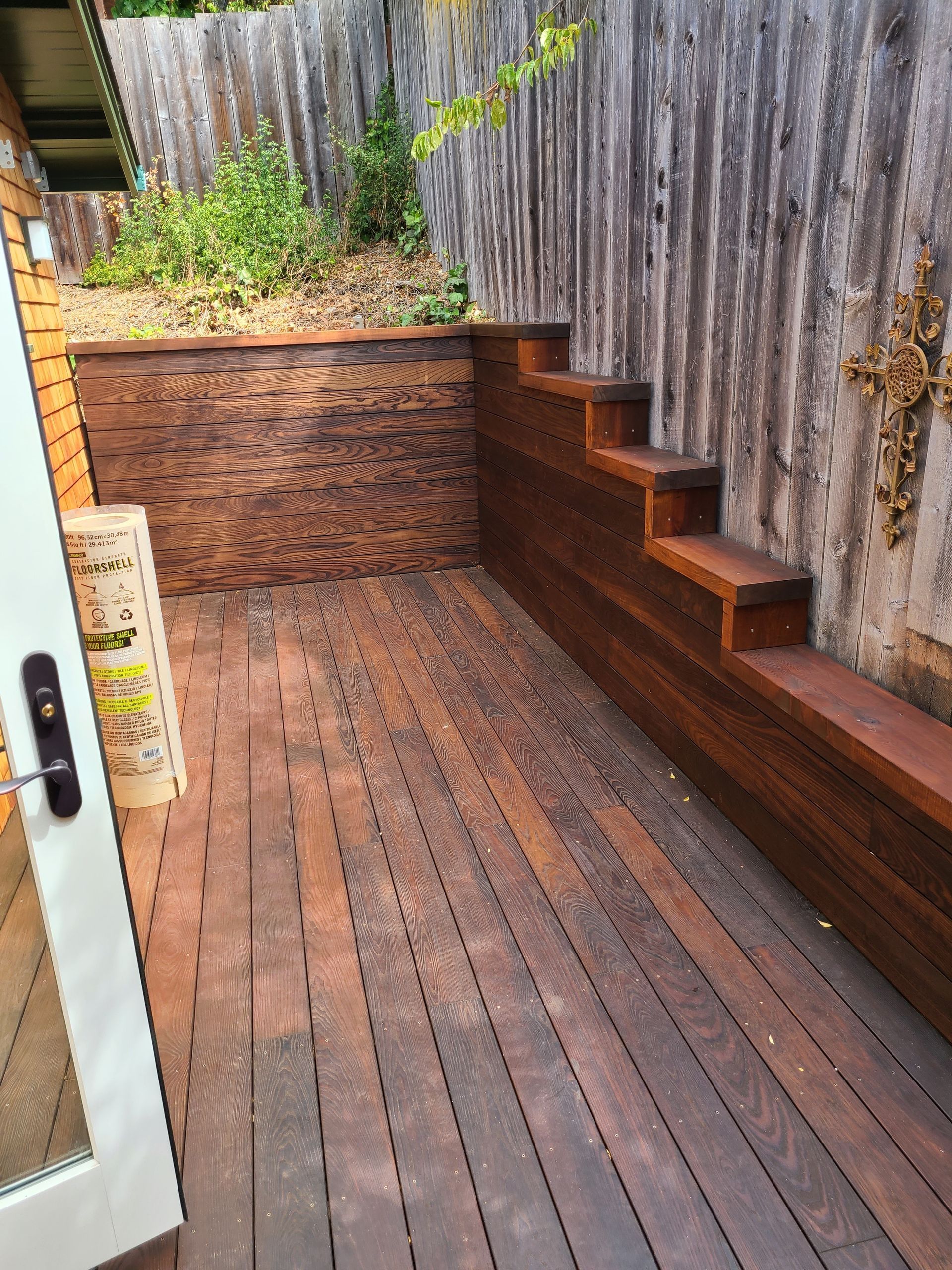 A wooden deck with stairs leading up to it next to a wooden fence.