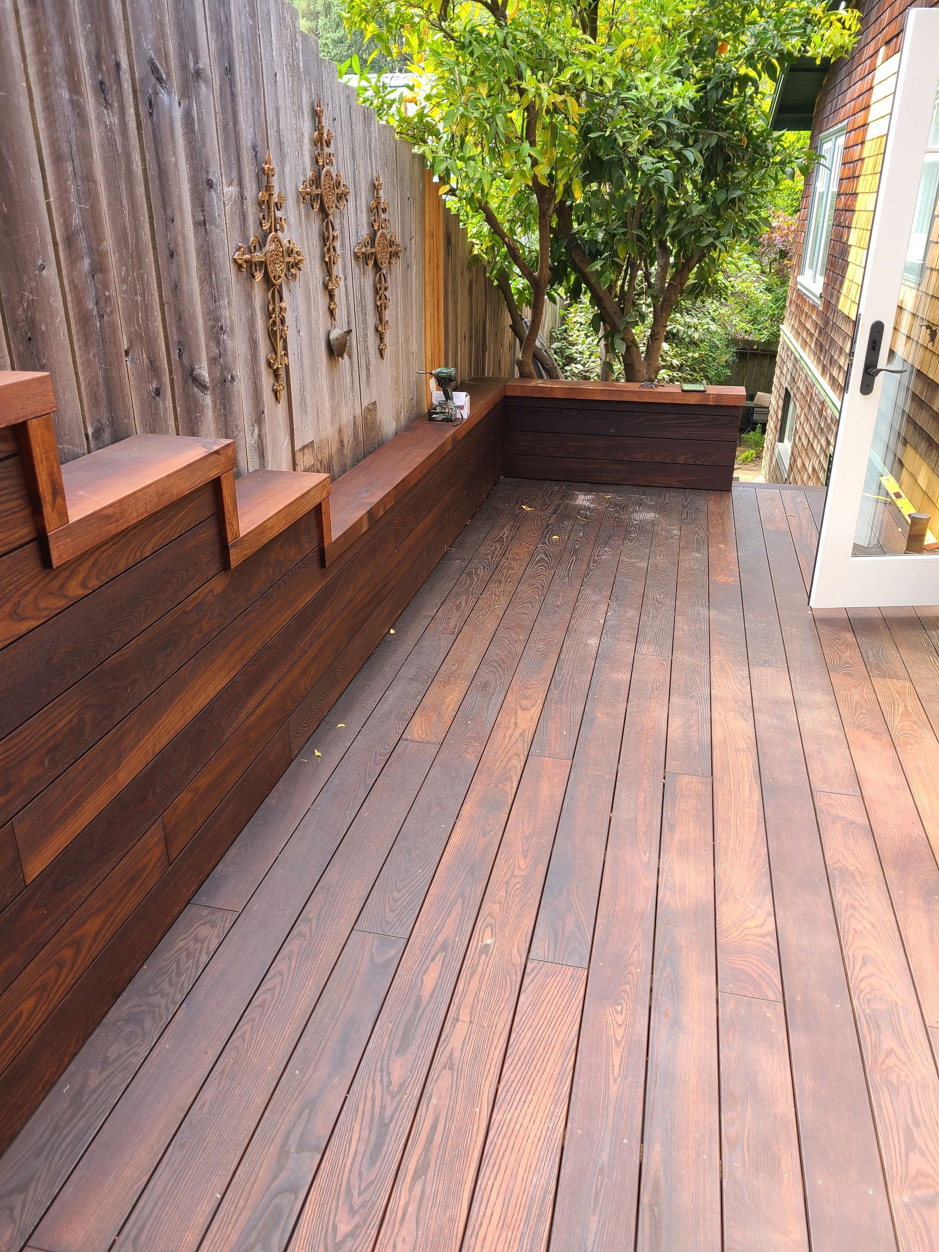 A wooden deck with a bench and stairs next to a wooden fence.