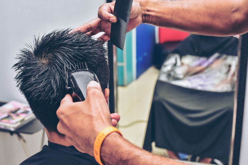 A Man is Getting His Hair Cut by a Barber in Front of a Mirror — Barbarella Hair in Maryborough, QLD