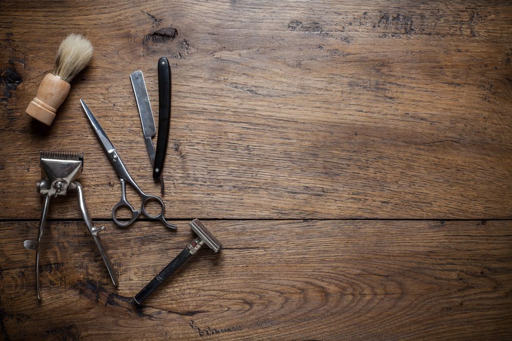 A Wooden Table Topped With a Razor, Scissors and a Shaving Brush — Barbarella Hair in Maryborough, QLD