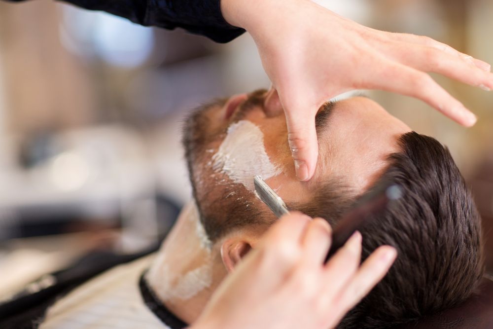 A Man is Getting His Beard Shaved by a Barber in a Barber Shop — Barbarella Hair in Maryborough, QLD
