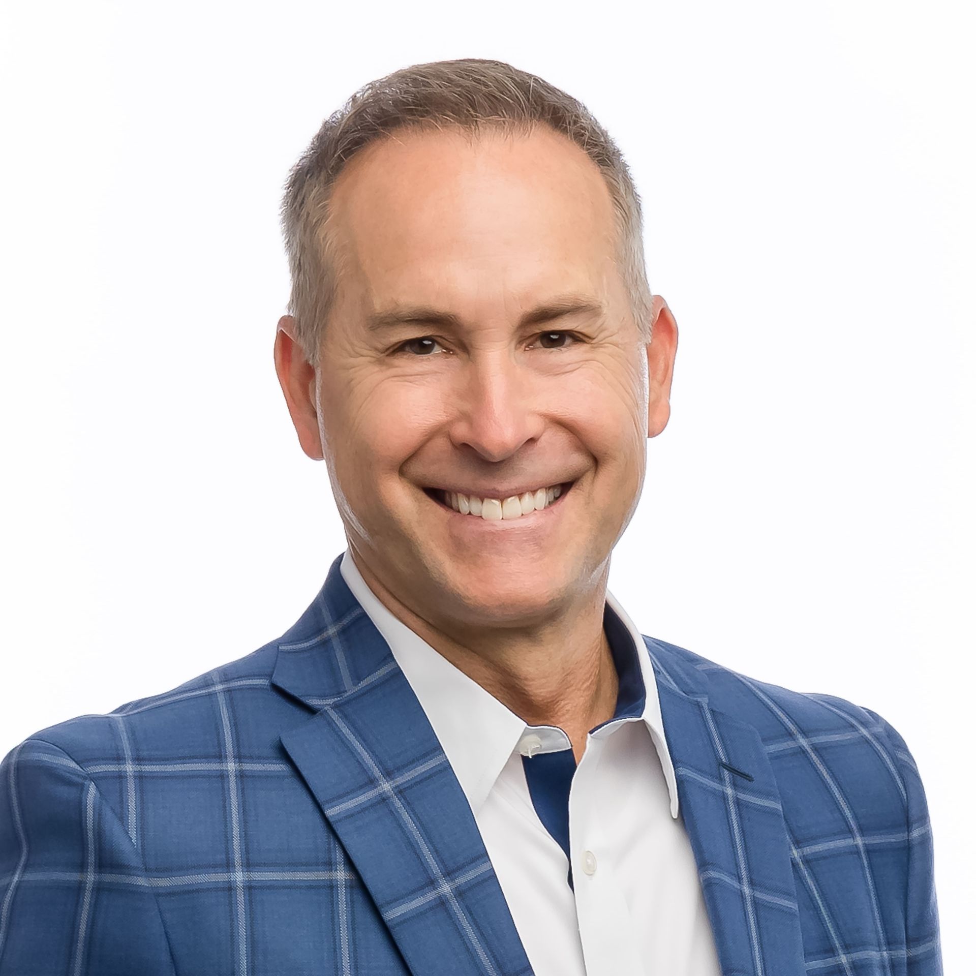 A smiling person in a blue plaid blazer and white collared shirt against a plain white background.