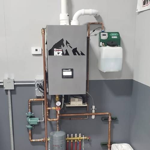 A room with a boiler and copper pipes on the wall.