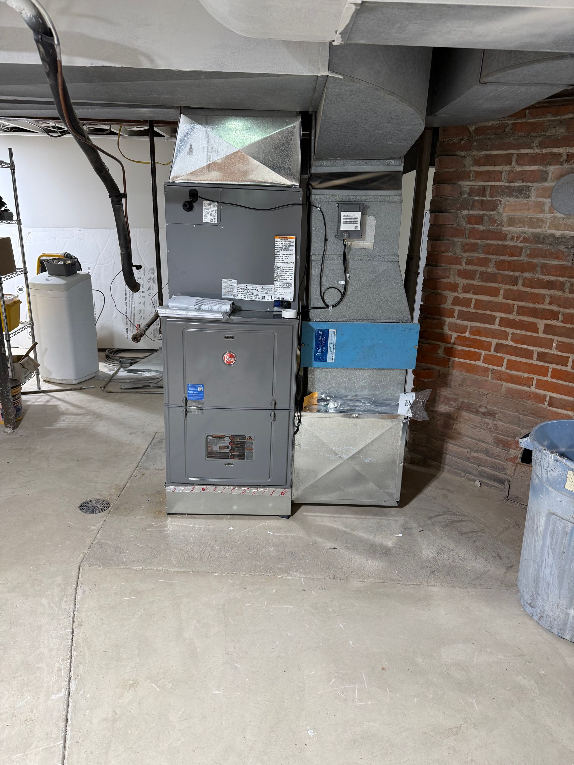 A man is working on an air conditioner outside of a brick building.
