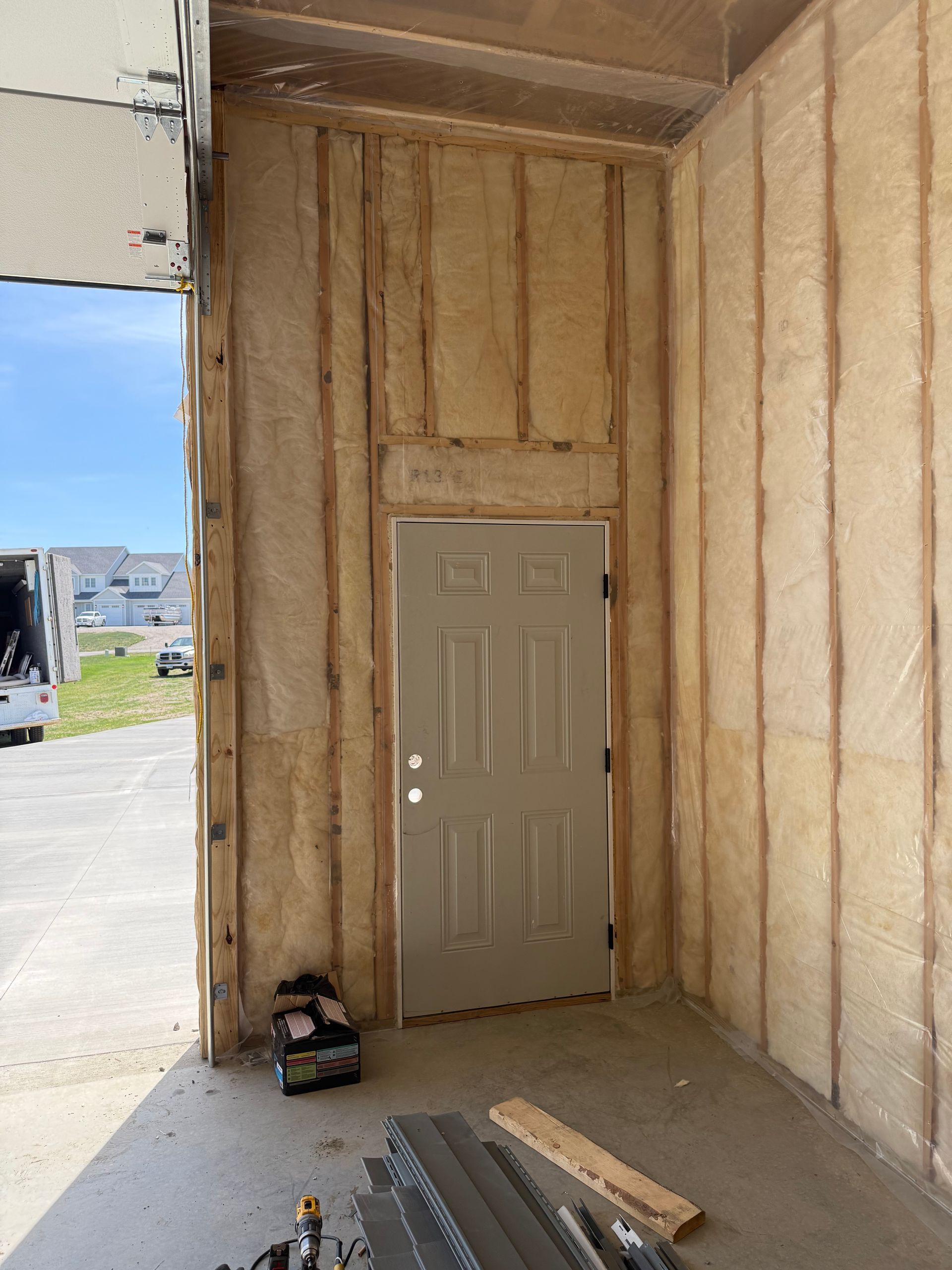 Interior framing of a doorway in an unfinished building, with a beige door and construction materials on the floor.