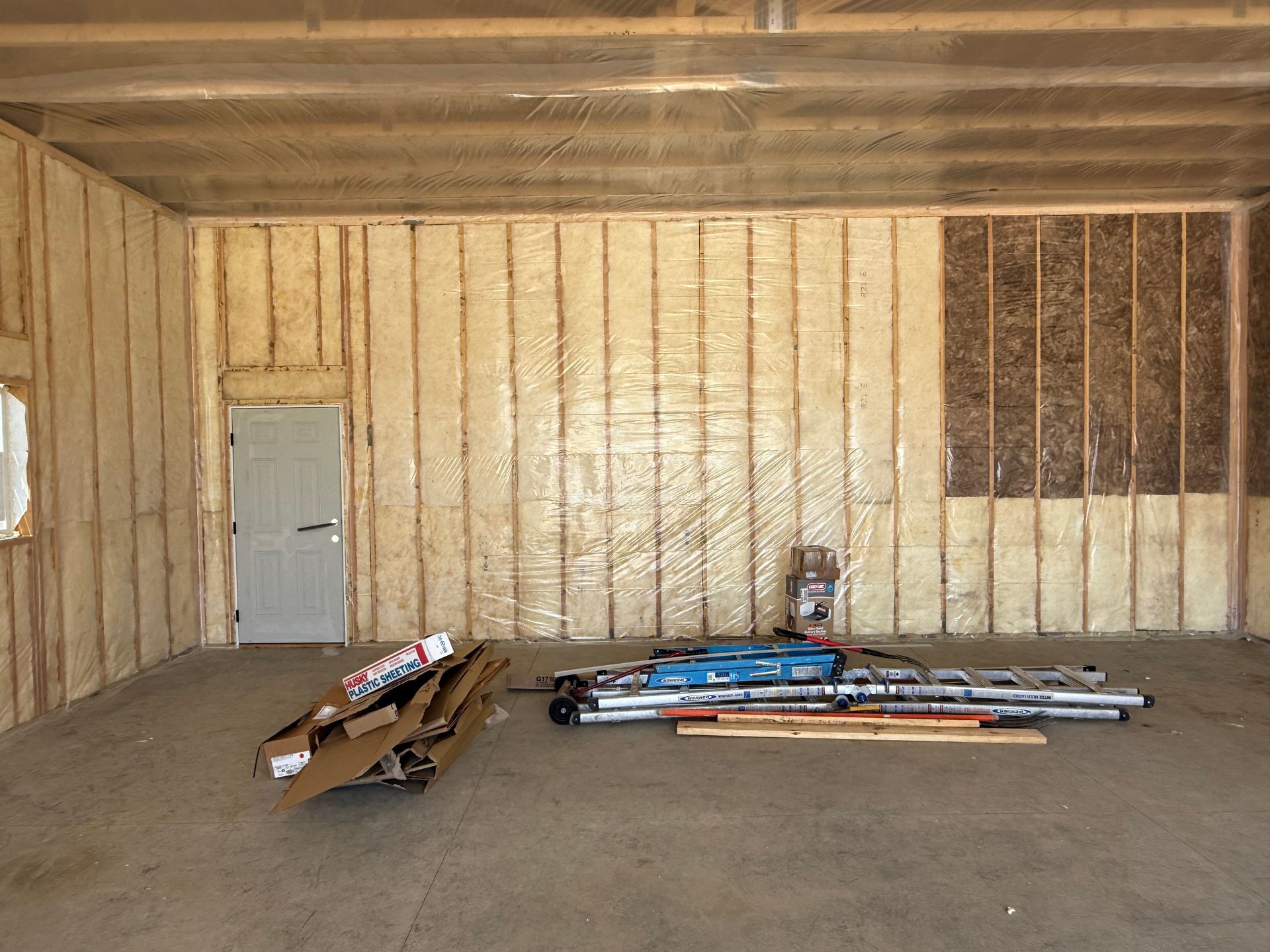 Wooden shipping container interior with scattered cardboard boxes and long metal pipes on the floor