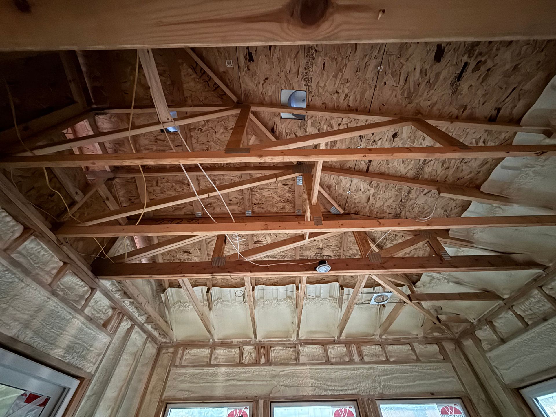 Wooden roof trusses and insulation inside an unfinished attic or room ceiling