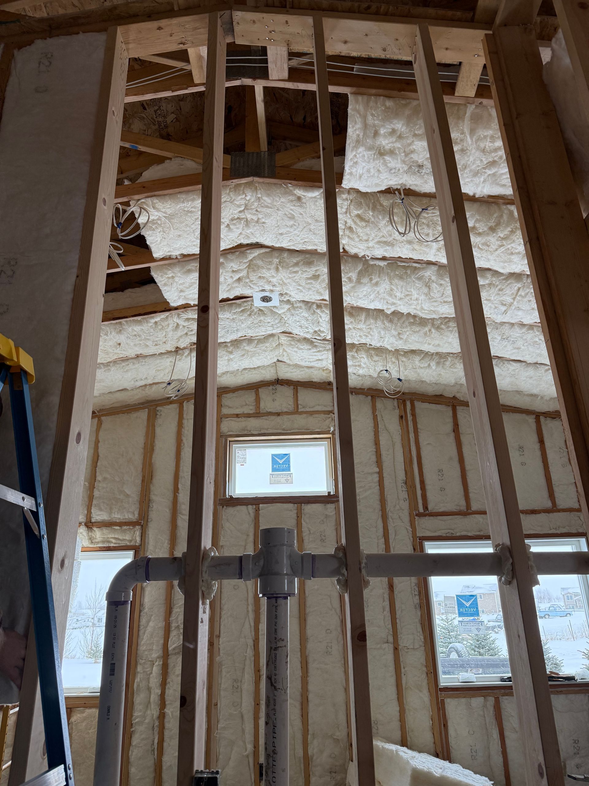Exposed wall framing and spray foam insulation inside a house under construction
