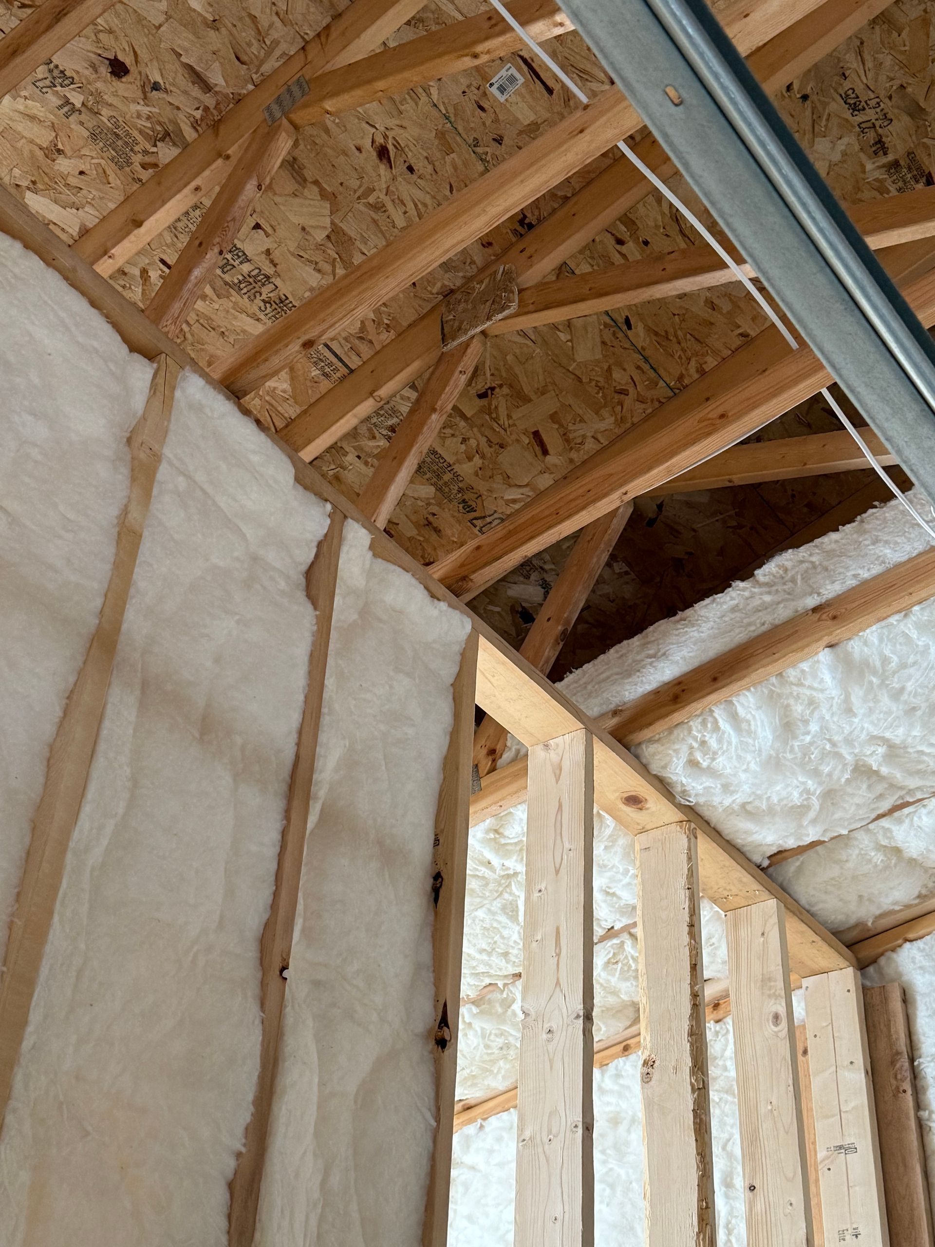 Insulated attic with exposed wooden roof trusses and framing under construction
