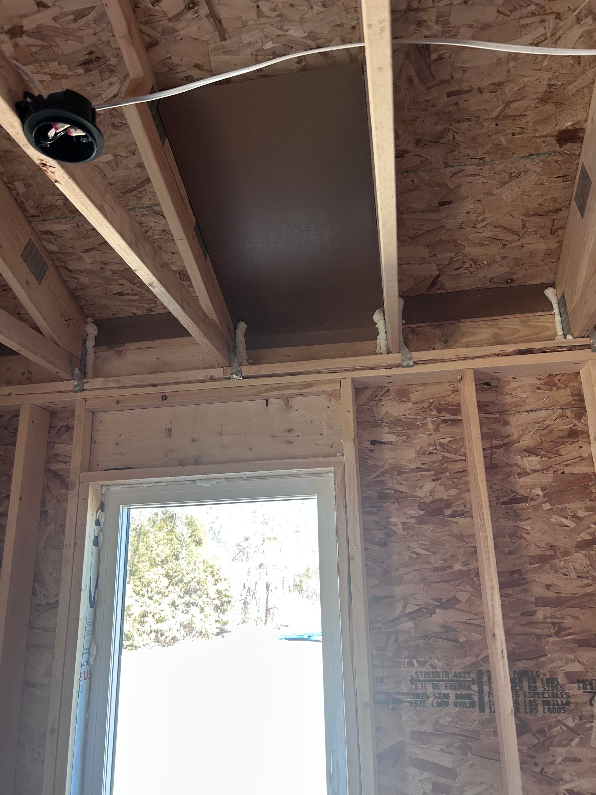 Unfinished room with exposed wooden framing, OSB ceiling, and a bright open doorway.