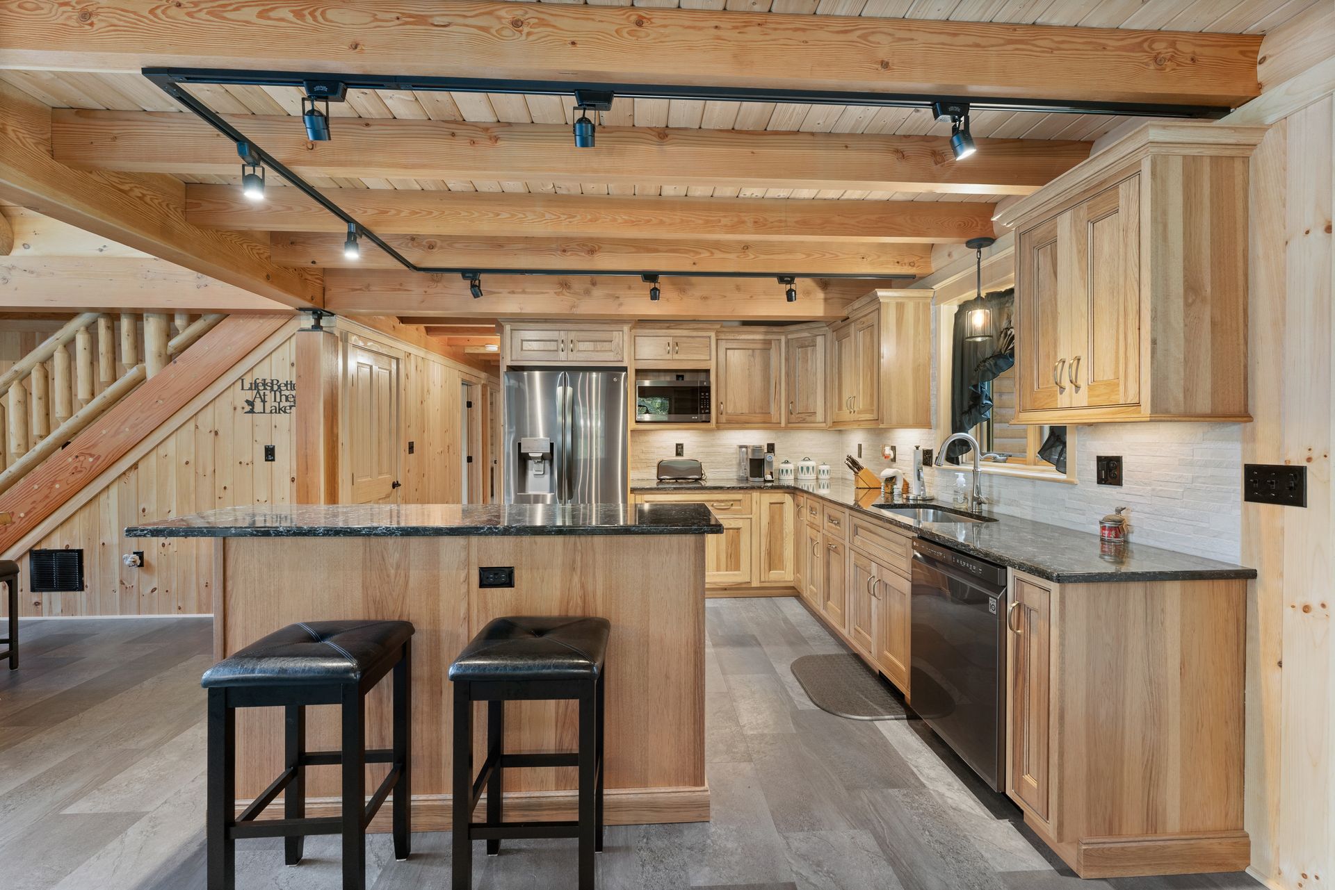 A kitchen in a log cabin with wooden cabinets and stools.