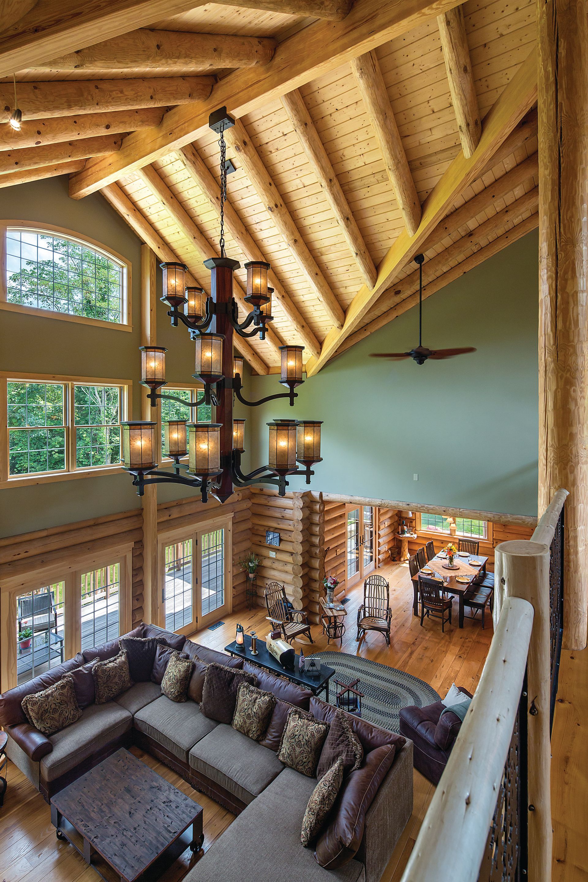A living room in a log cabin with a chandelier hanging from the ceiling.