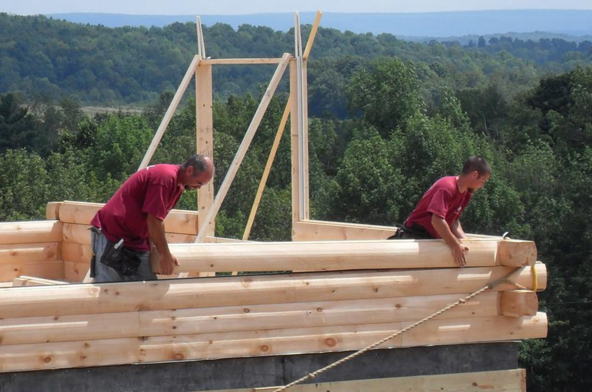Two men are working on constructing a log home