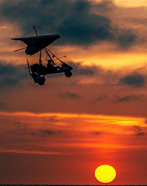 Small paraglider with engine flying during the sunset