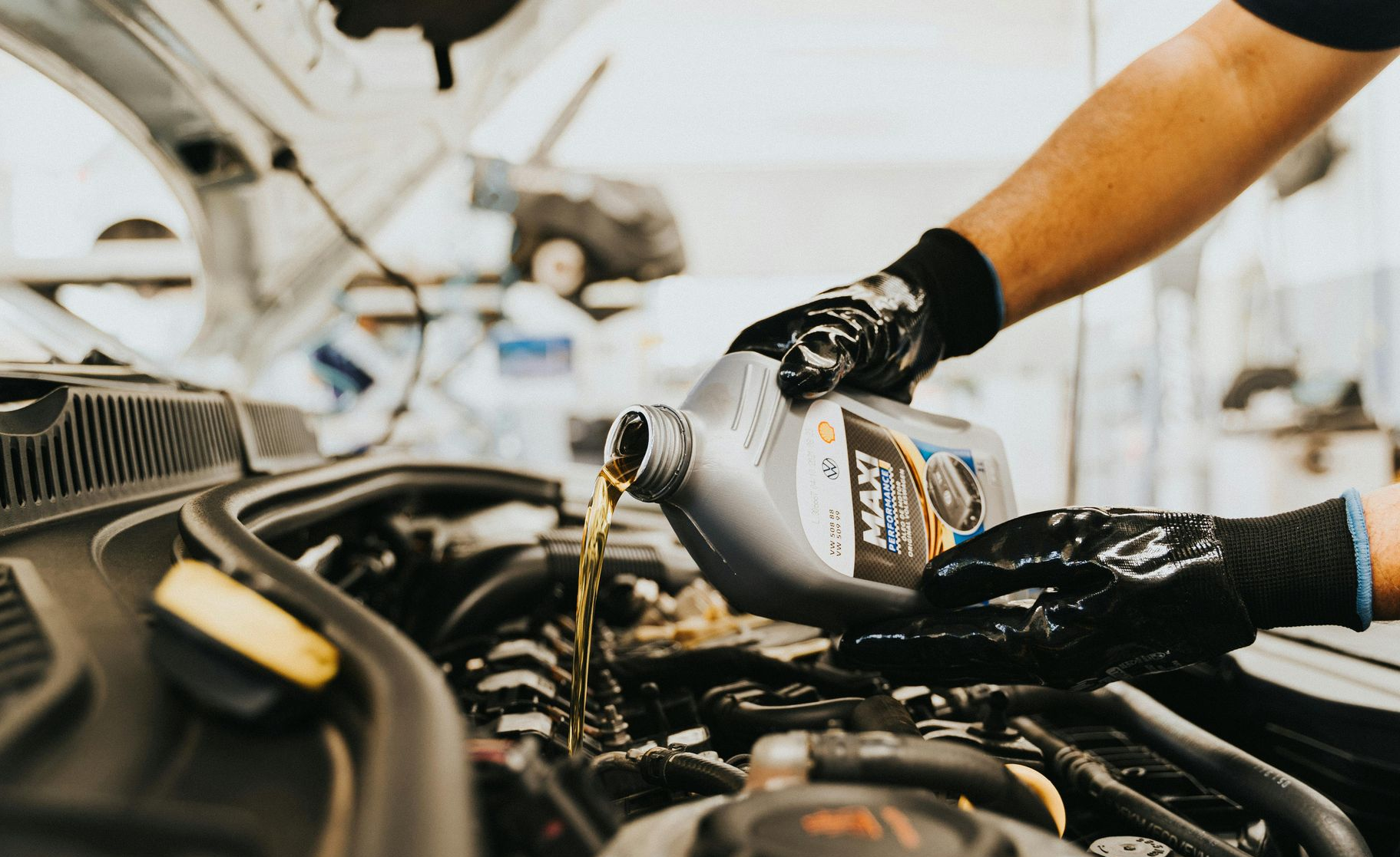 Mechanic pouring fresh engine oil into a car engine.