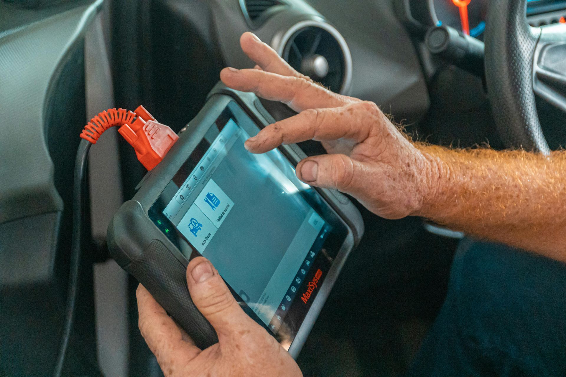 Mechanic using an Autel MaxiSys car diagnostic tablet.