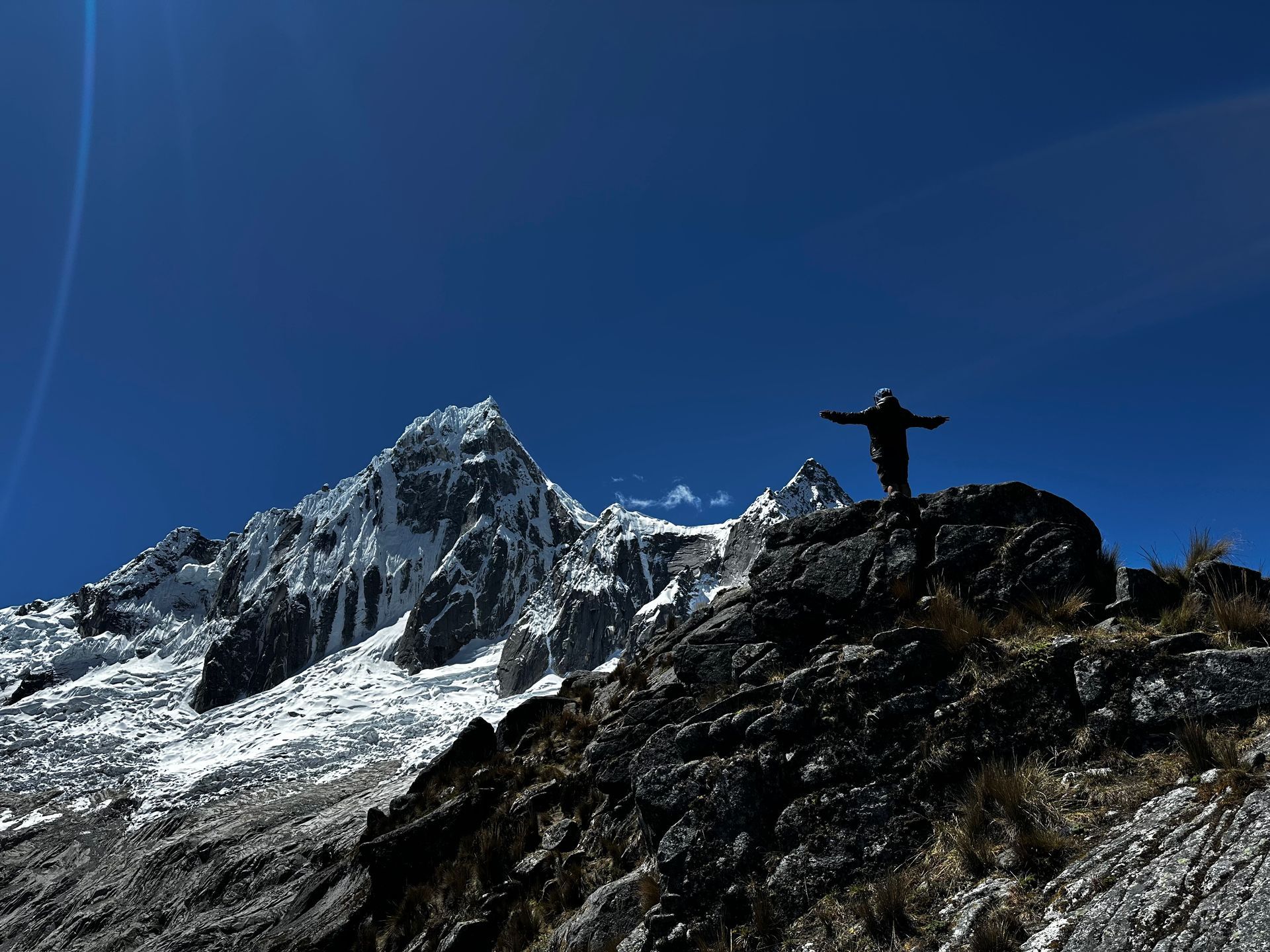 hiker on top of punta union overlooking a snowy mountain 