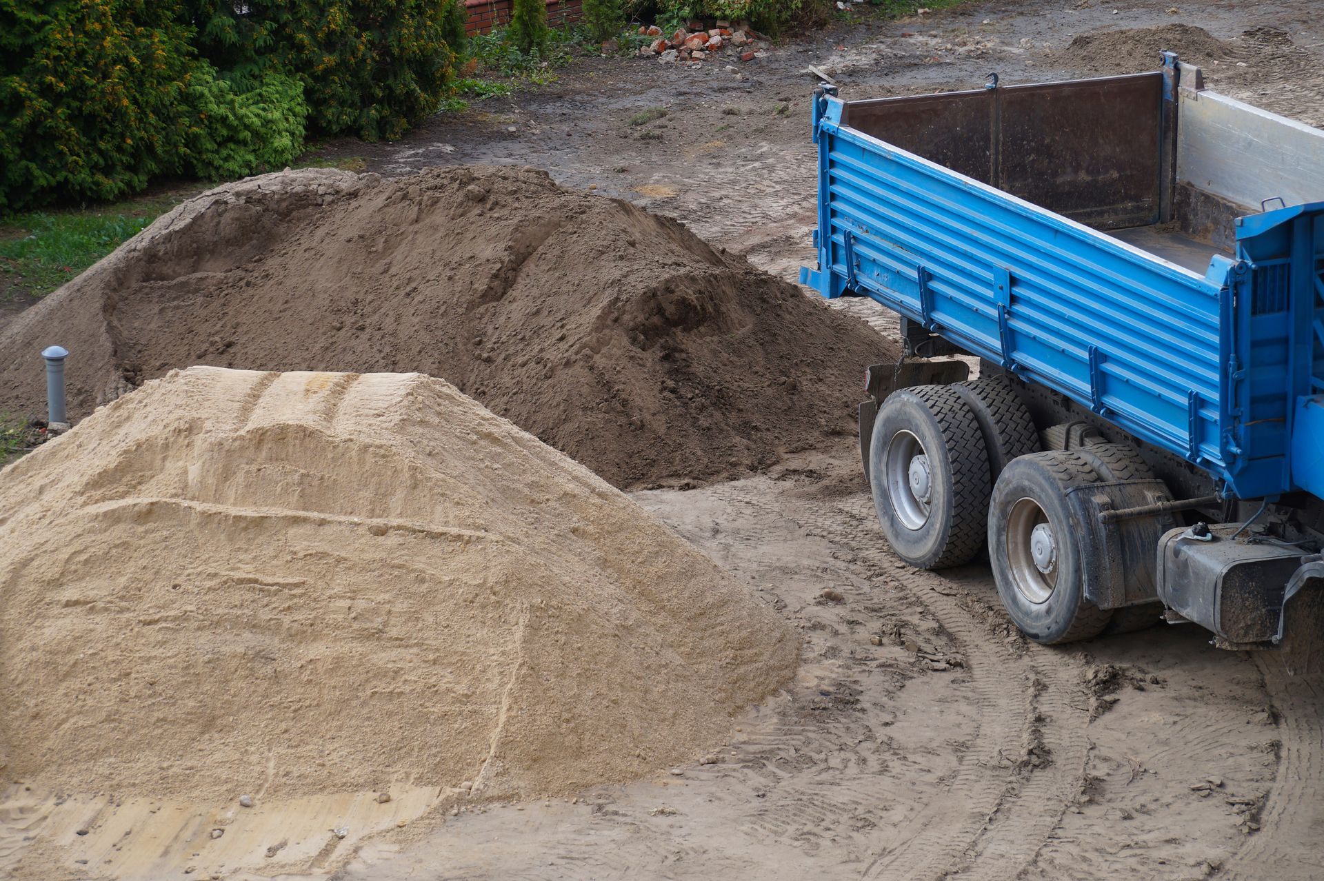 Large truck delivering soil and sand for construction project.