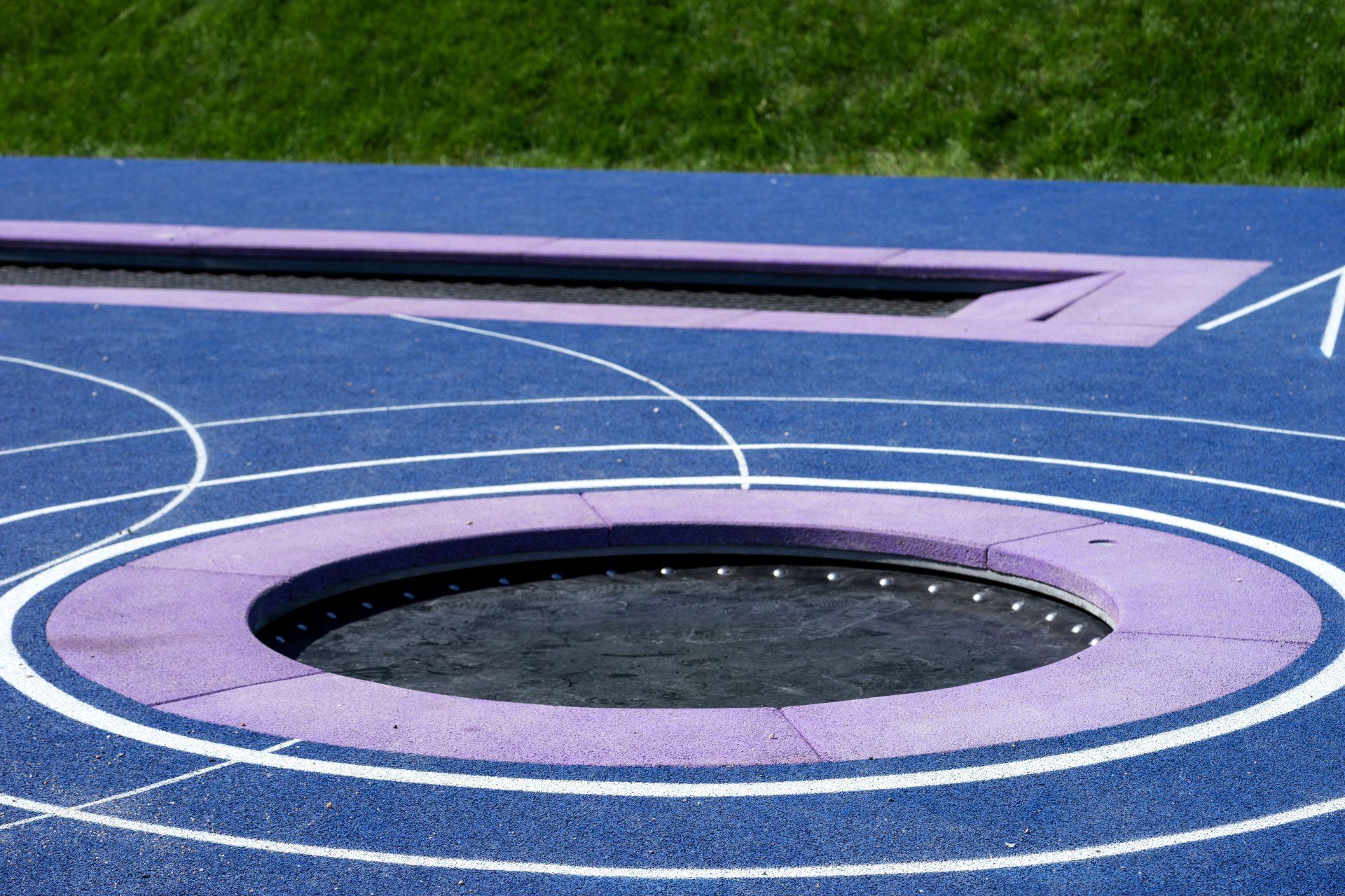 An in-ground trampoline set into a lush green backyard.