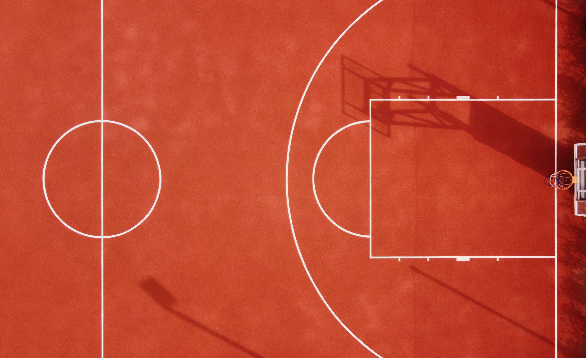 Vibrant red basketball court with a crisp white outline, ready for an exciting game.