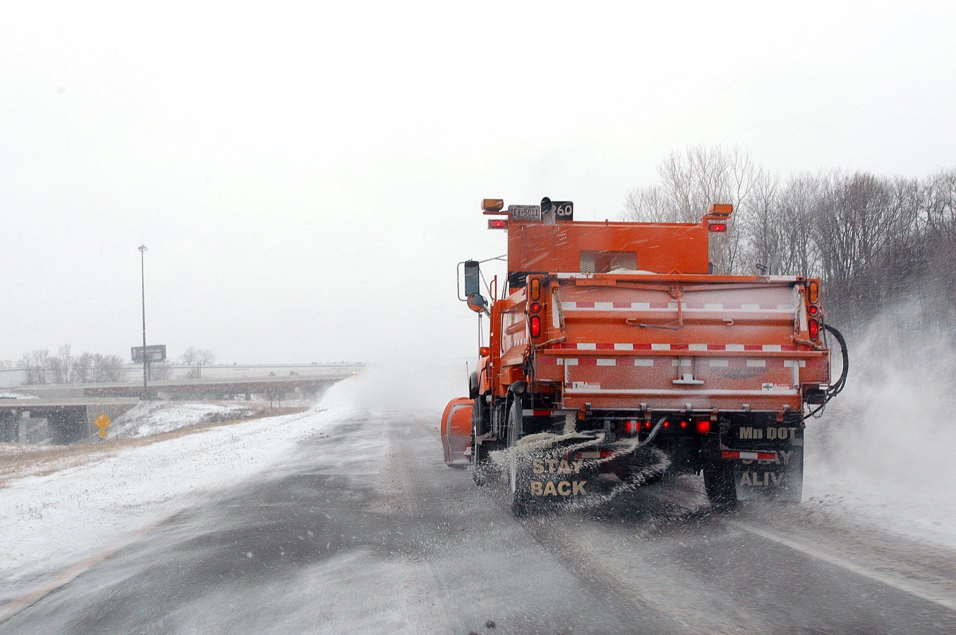 Snow plow clearing and salting a snowy street during winter to ensure safe driving conditions.