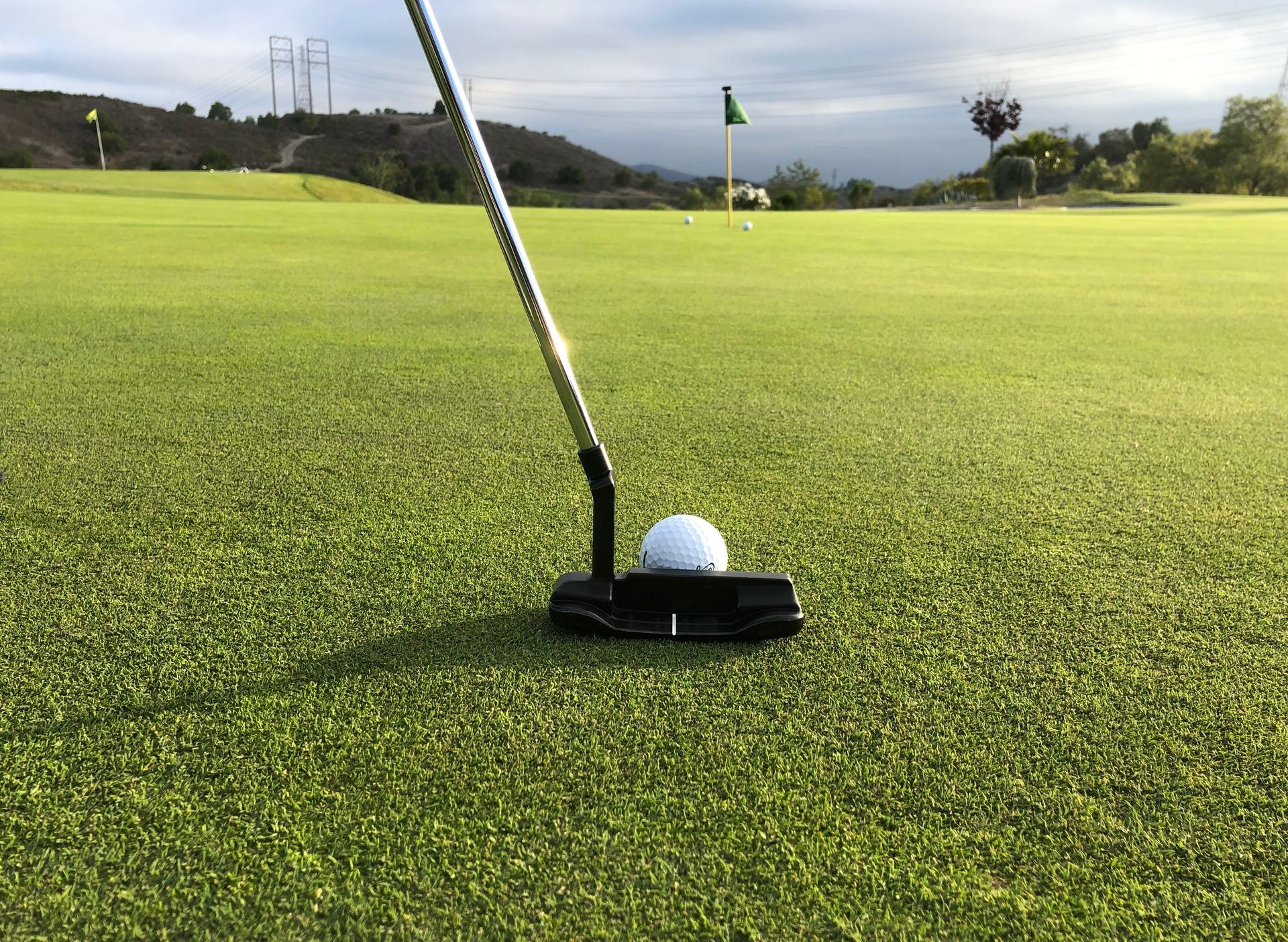 White golf ball resting on the lush green fairway of a golf course, ready to be teed off.