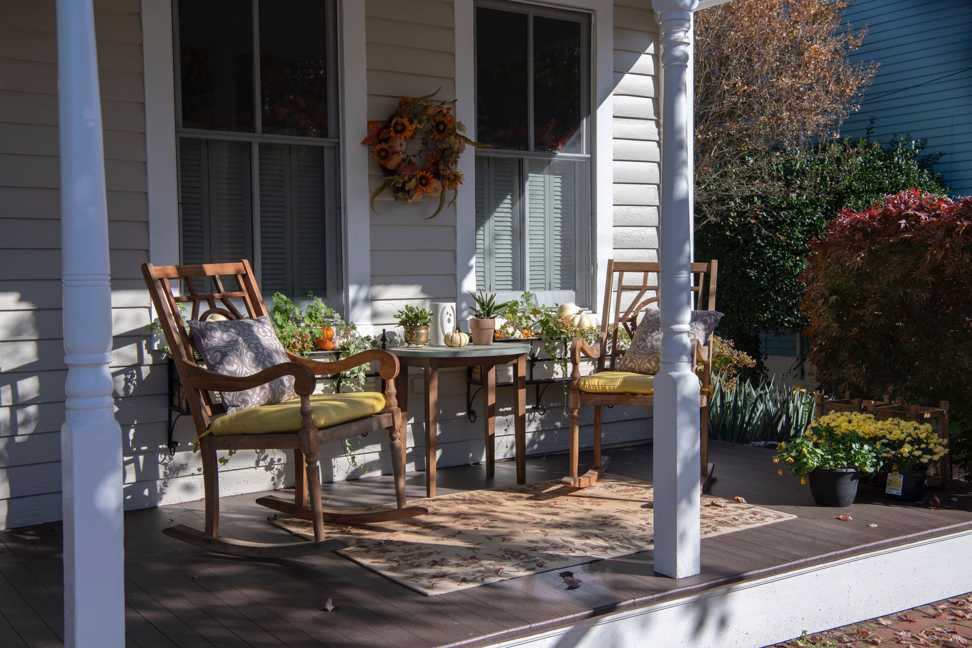Wooden table and chairs arranged on a sunlit wooden porch, creating a cozy outdoor seating area.
