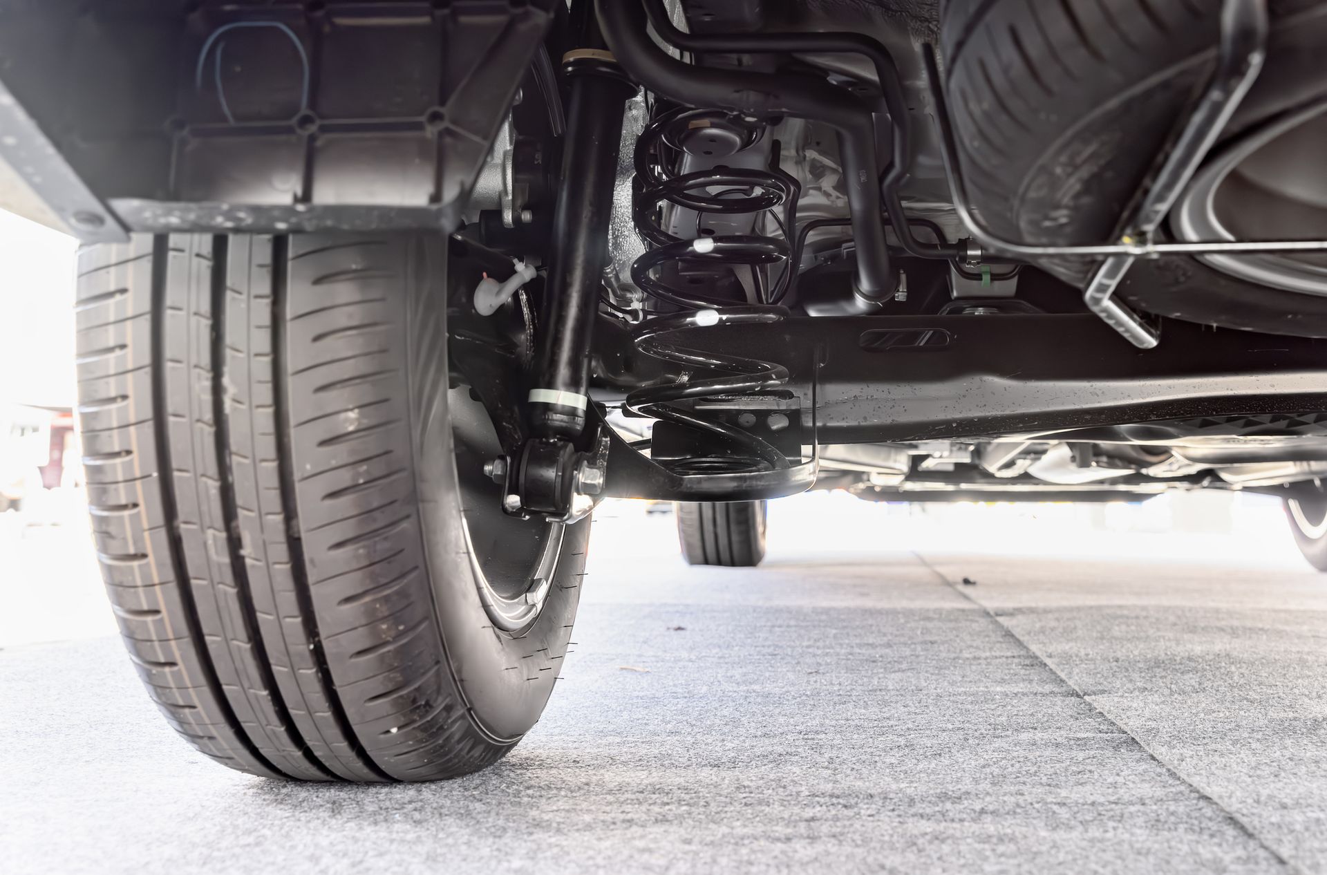 A close up of the underside of a car with a tire and suspension.