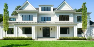 A large white house with a lush green lawn in front of it