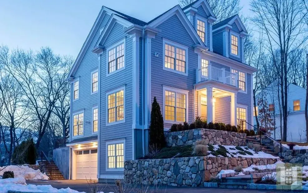 A large house with a lot of windows is sitting on top of a snow covered hill.